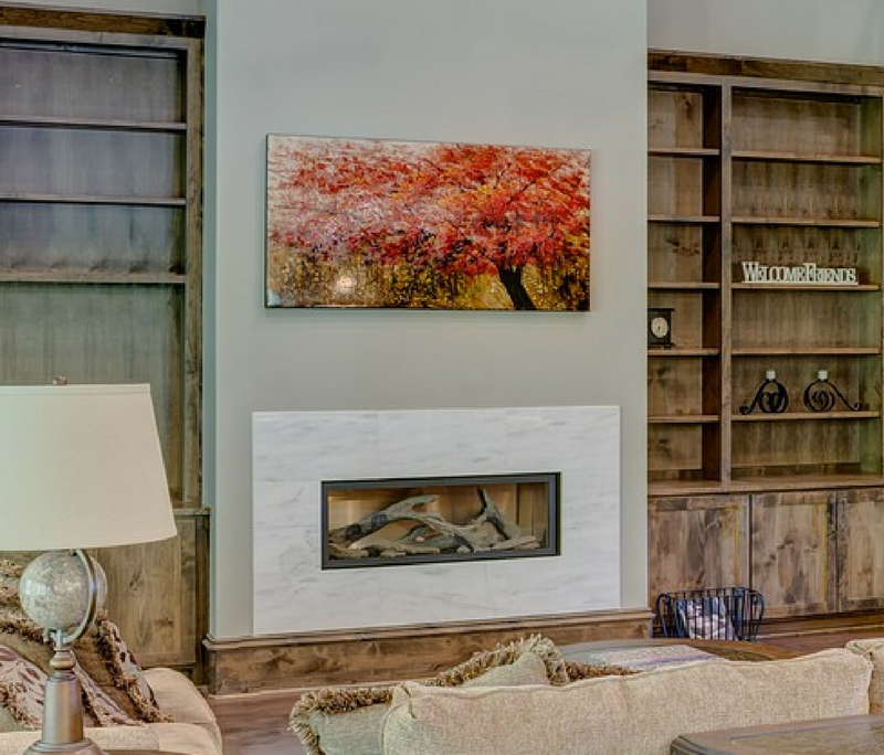 Comfortable room with neutral tones and wood bookcases } Bright orange tone painting over fireplace
