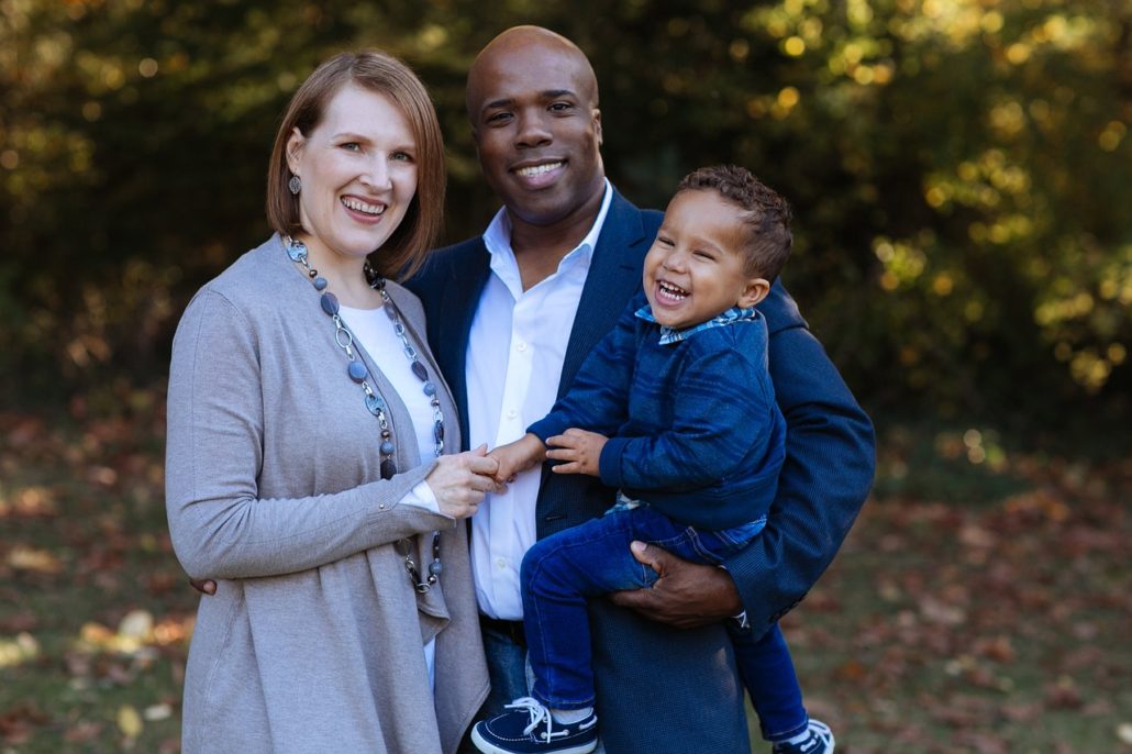 Smiling couple posing for family photo with man holding their young son